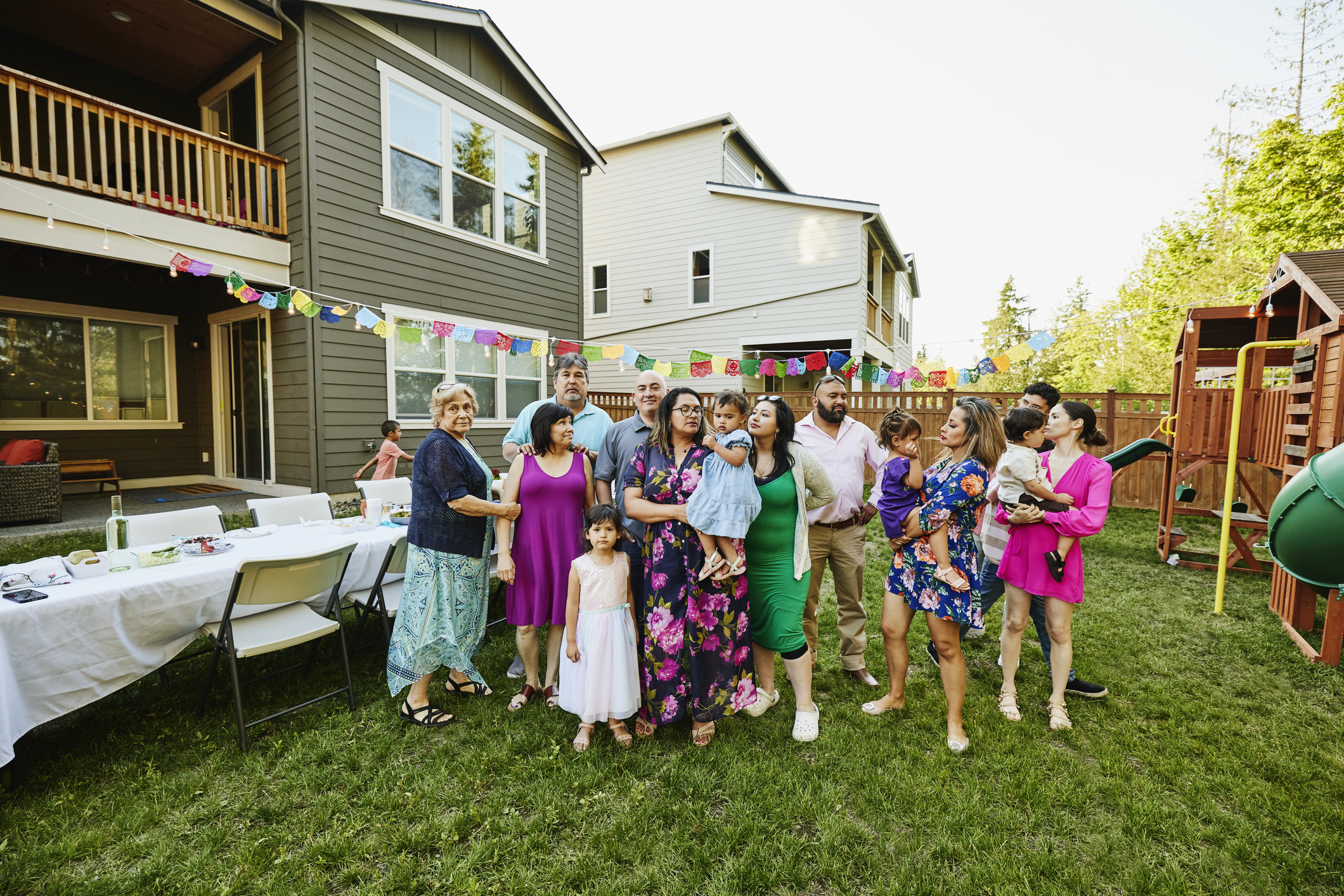 Wide shot portrait of multigenerational family during backyard birthday party on summer evening