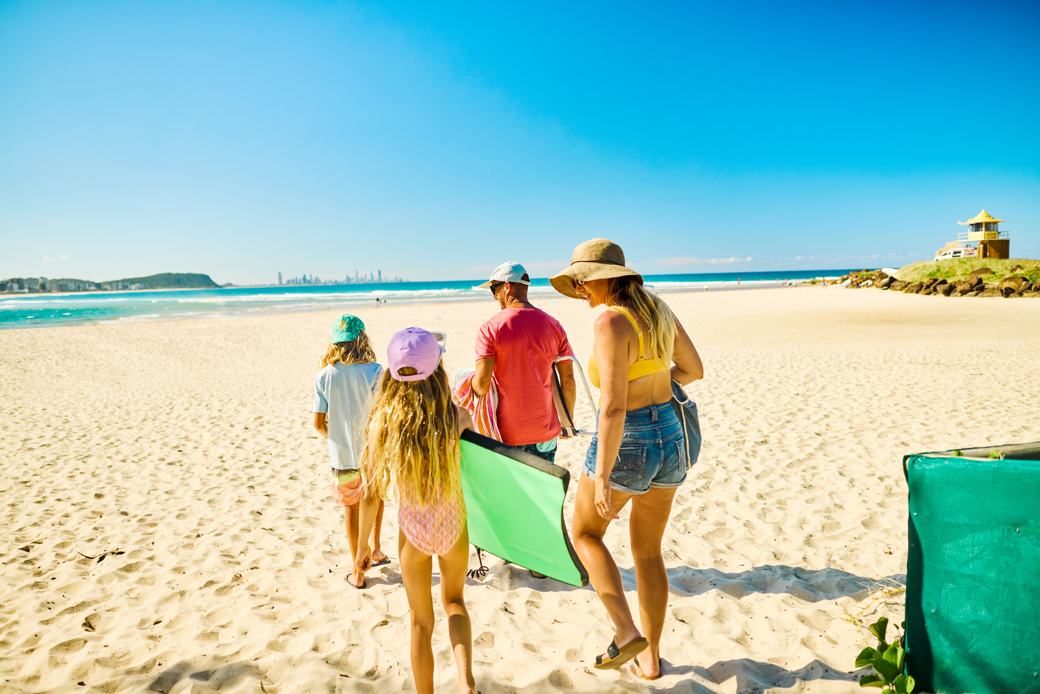 Family walking on the sand, carrying their beach gear, enjoying summer vacations in australia