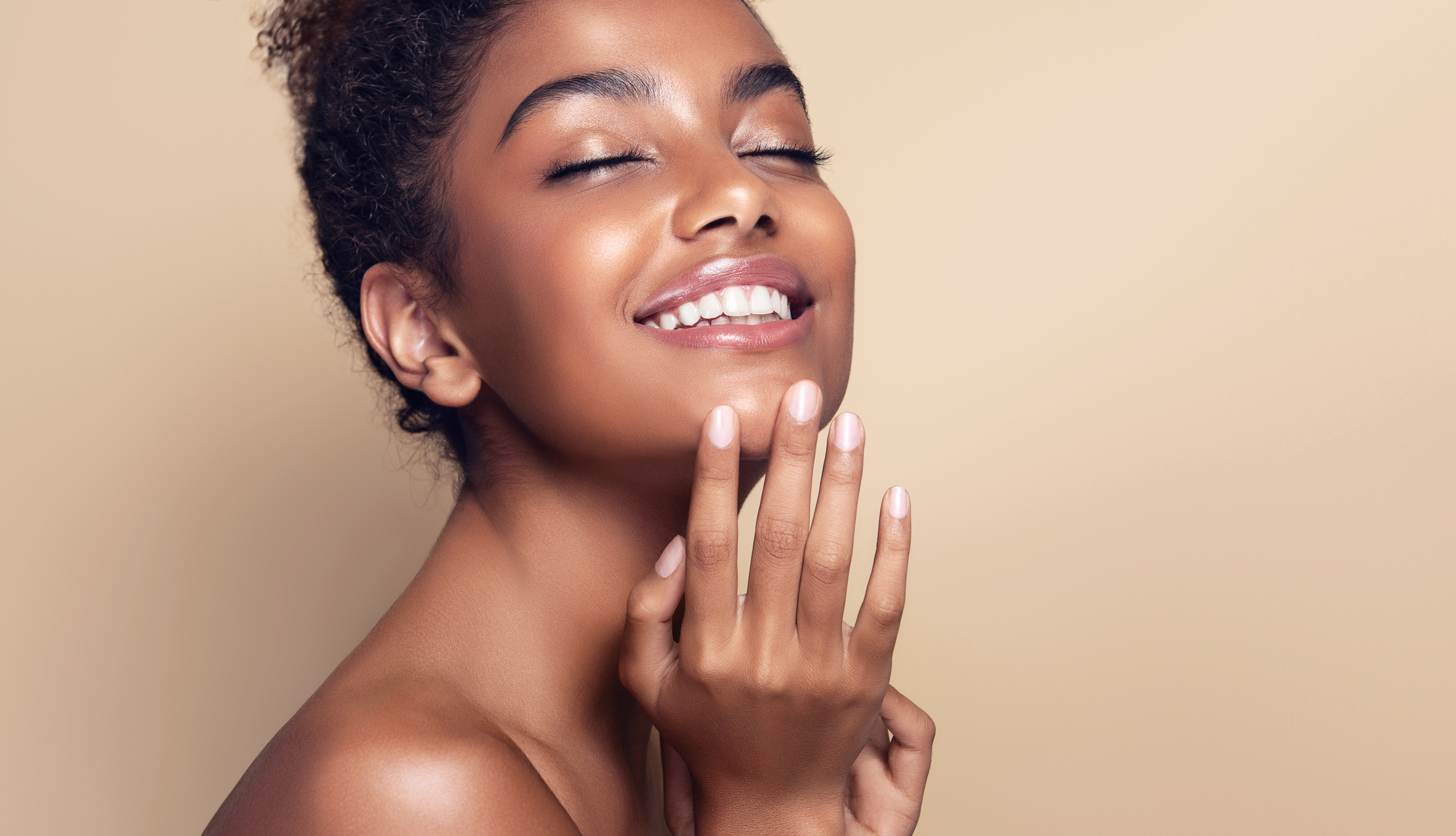 Portrait of perfectly looking black haired young woman. Natural long dense and curly Afro hair on the head of young beautiful model, white toothy smile on her face. Girl with vibrant, melanin-rich skin tone.