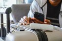 Cropped image of a South Asian man waiting in airport lounge charging his phone using power banks under $50 before departure. Focus on the foreground.