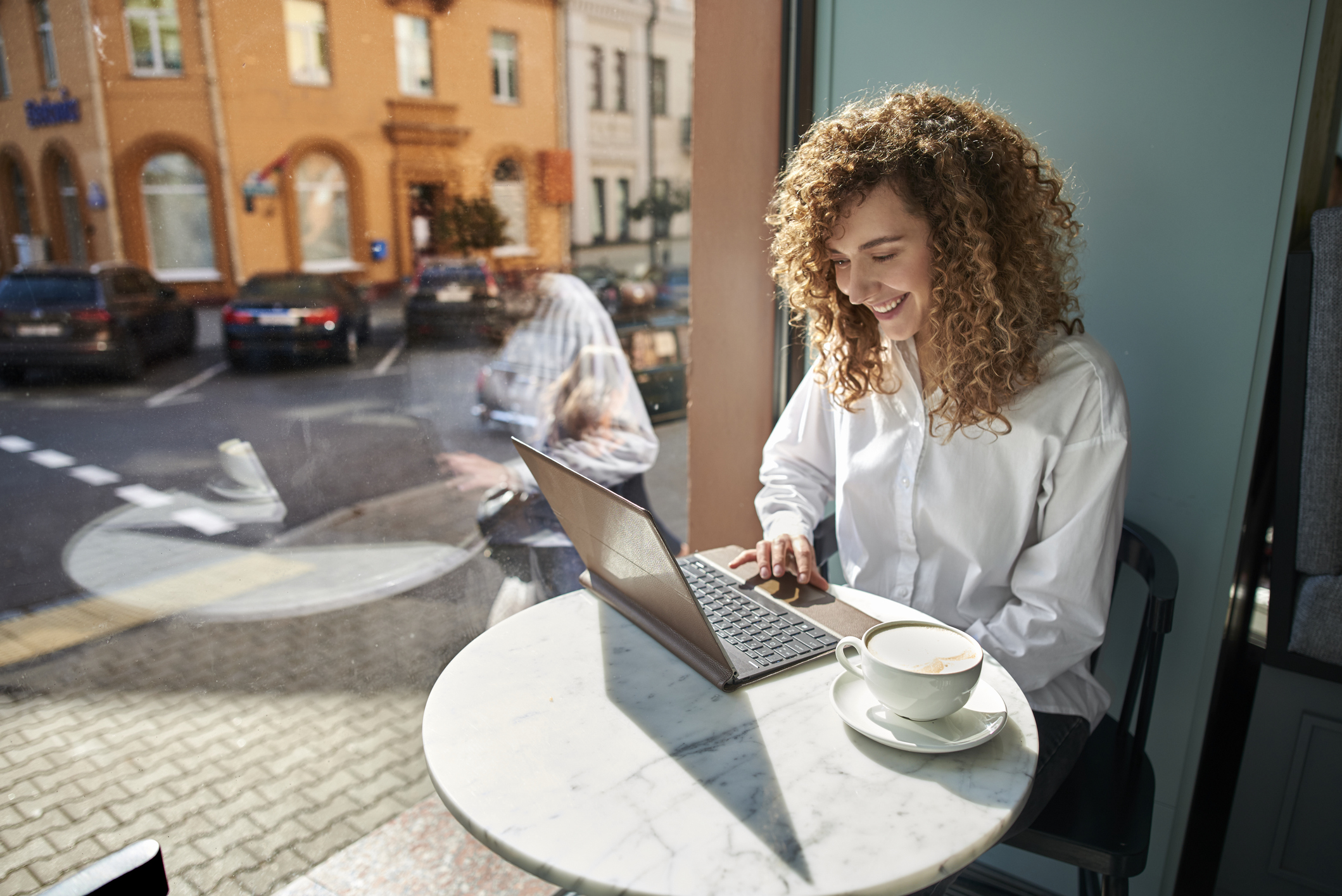 Smiling young woman using laptop in a cafe