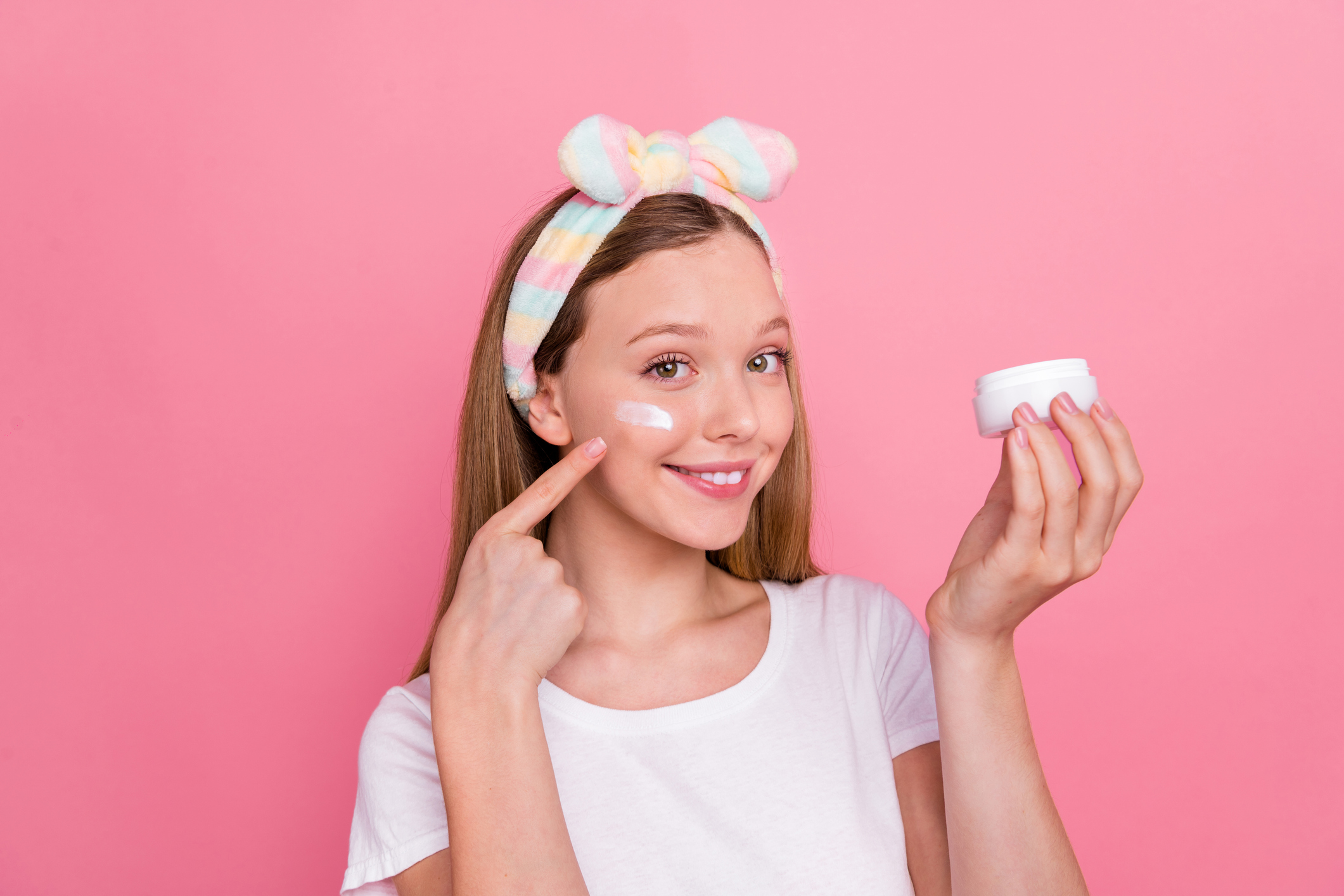 Portrait of adorable positive person hand hold peeling cream jar finger point apply cream under eye isolated on pink color background.