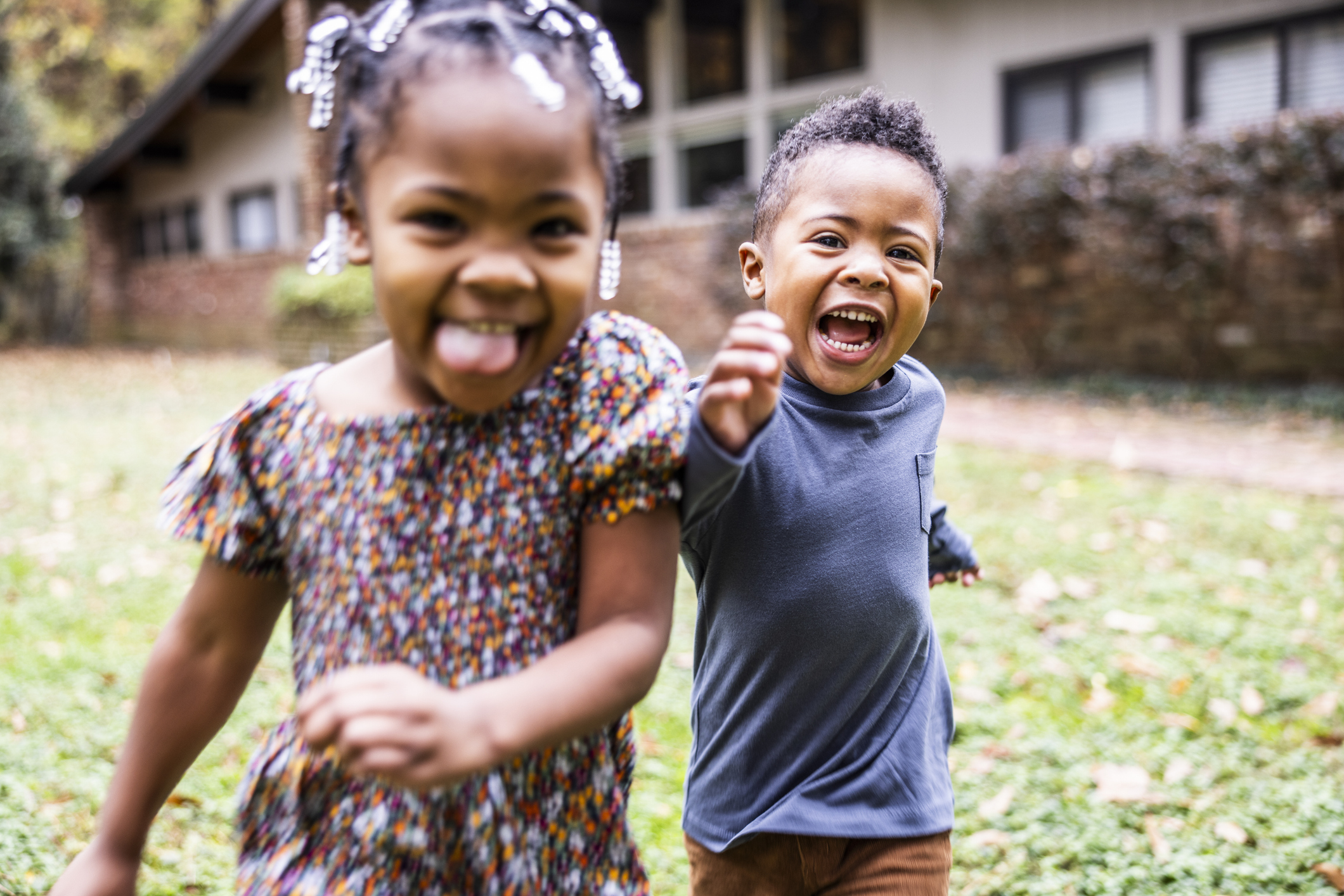 Brother and sister running in front of suburban home