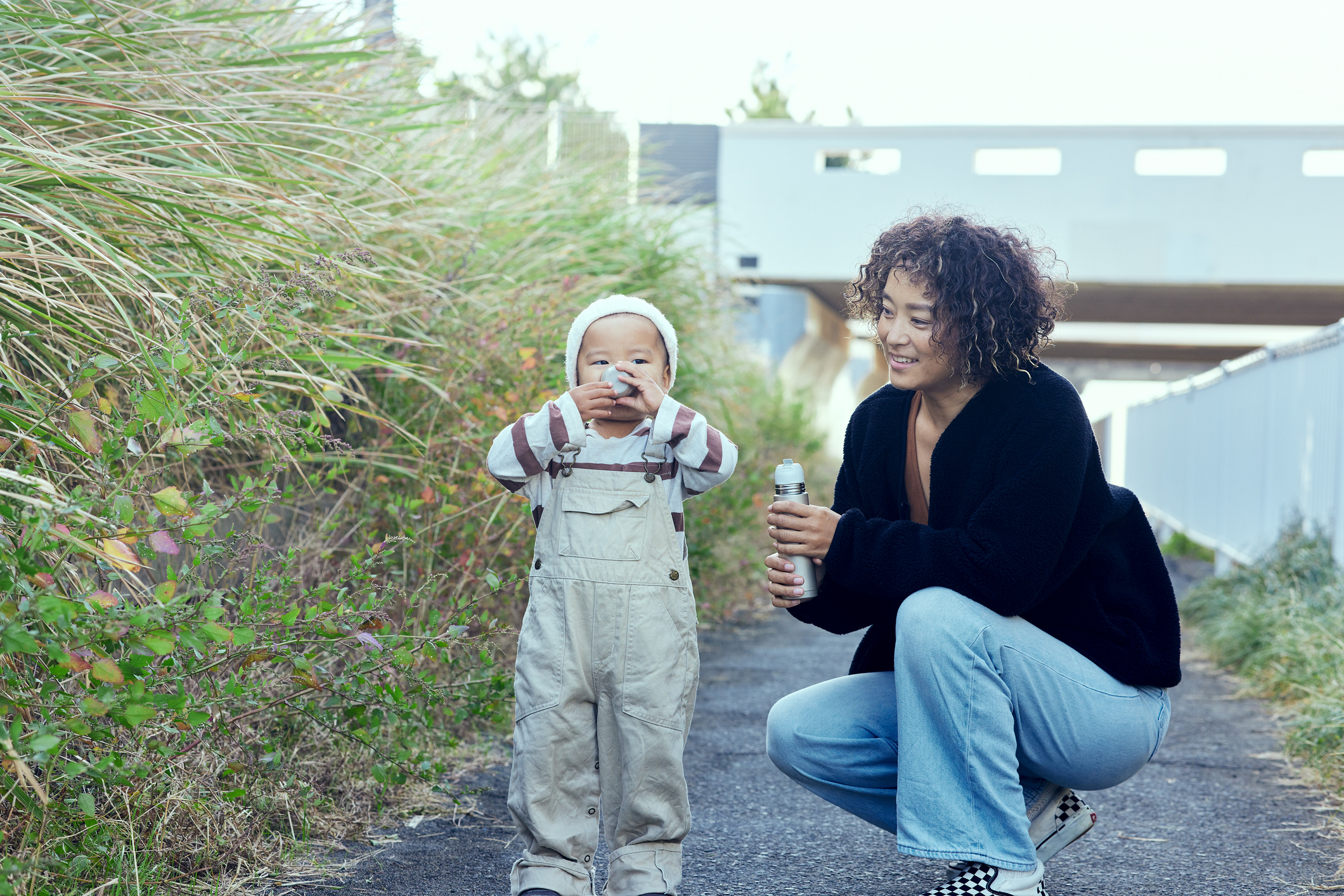 The little boy holds the cup in both hands.