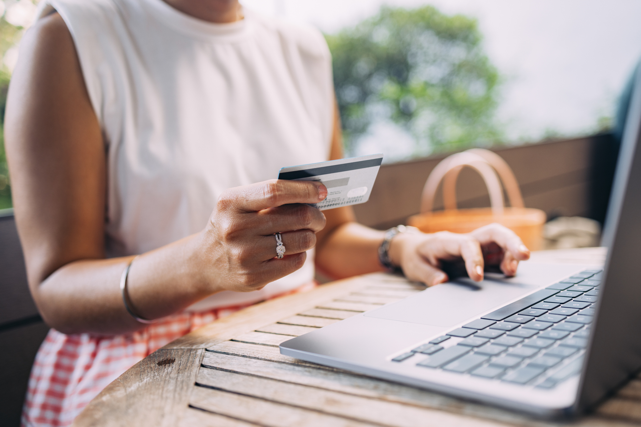 a female holding her credit card while paying something online on her computer.