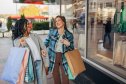 Outdoors fashion portrait of two beautiful women friends walking after shopping in the city