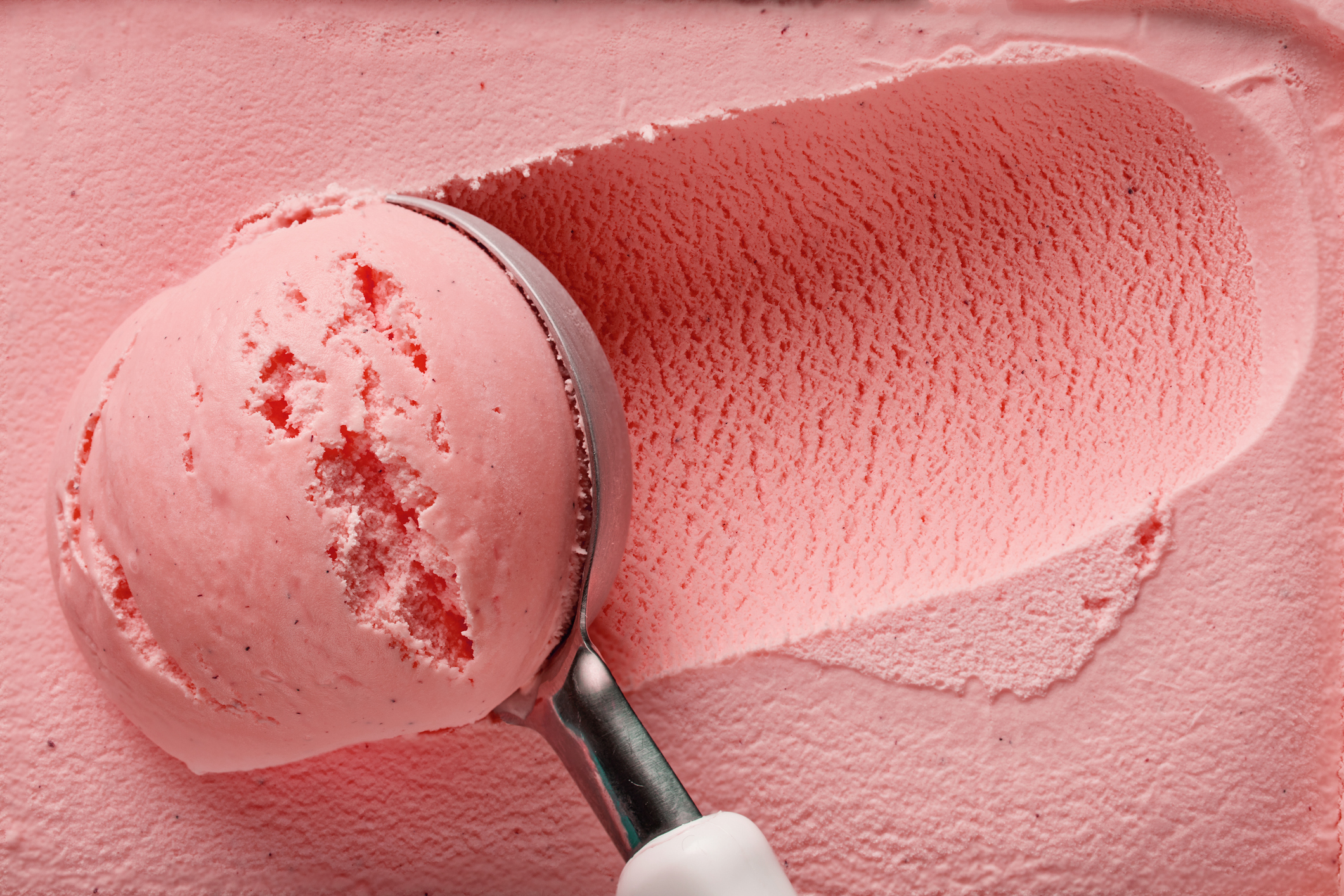 pink strawberry ice cream ball in a spoon, top view