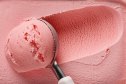 pink strawberry ice cream ball in a spoon, top view