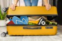 woman closes a full suitcase with things with both hands
