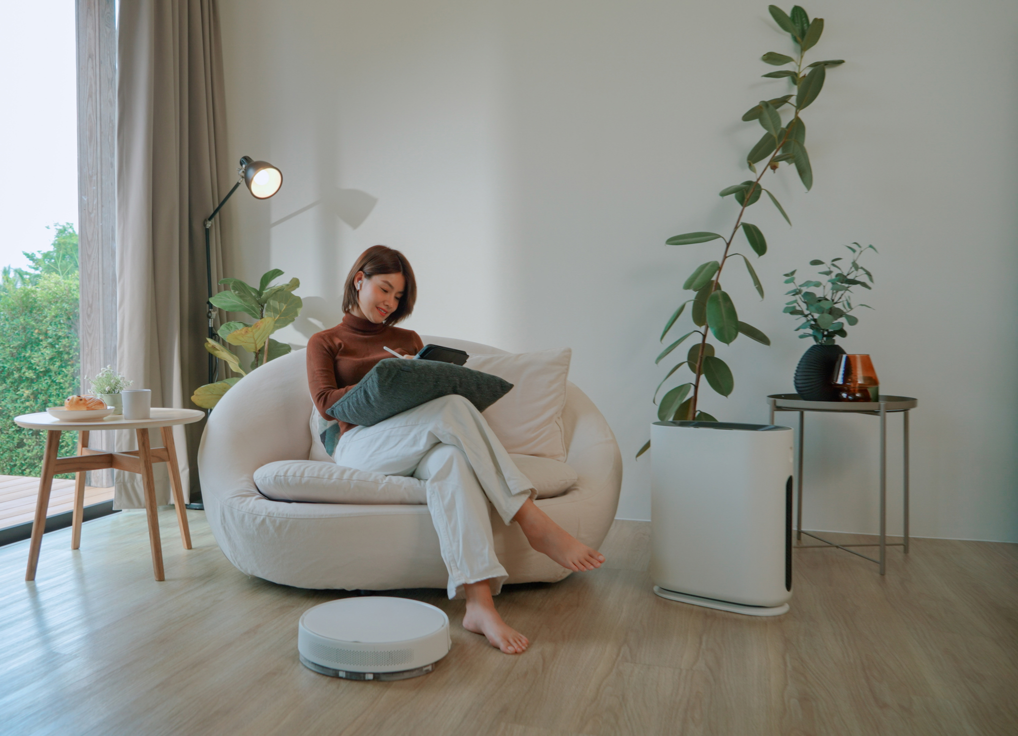 Asian woman working at home while vacuum cleaner and air purifier are working