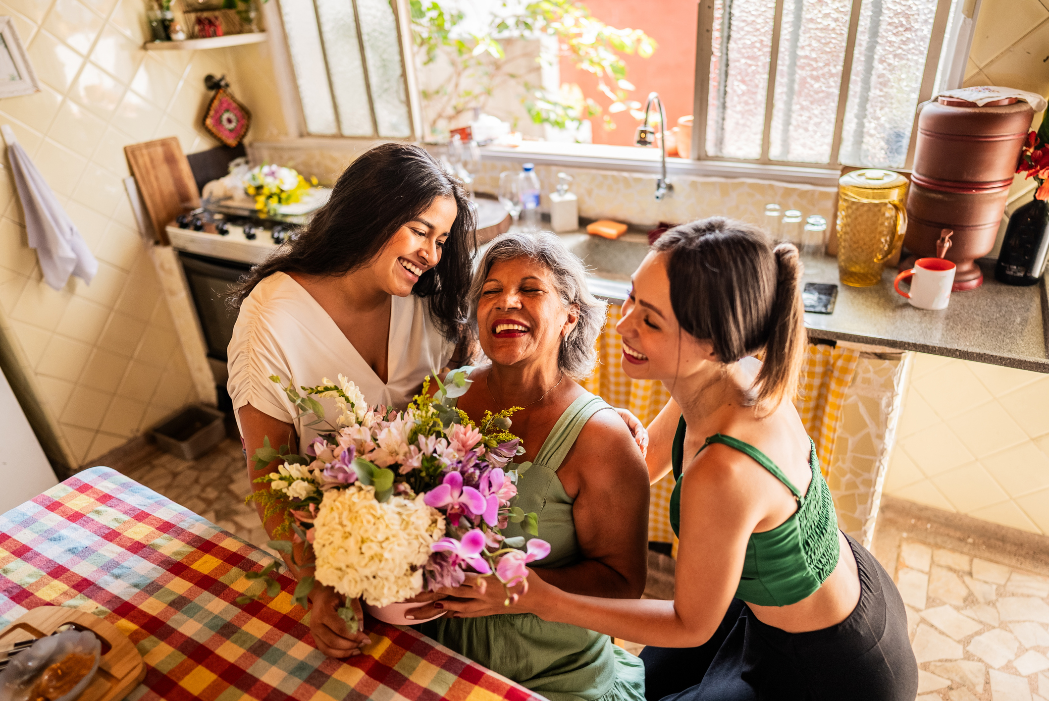 sisters giving flowers to grandmother at home