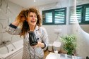 Smiling young woman in a bathrobe is drying her hair