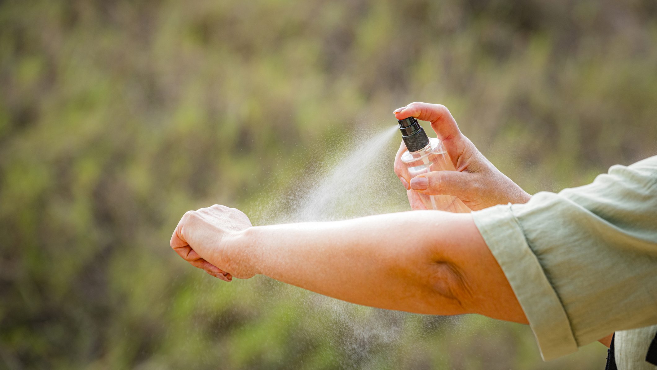 Woman spraying mosquito insect repellent on her arm