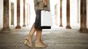 Woman carrying shopping bags in arcade, low section, rear view