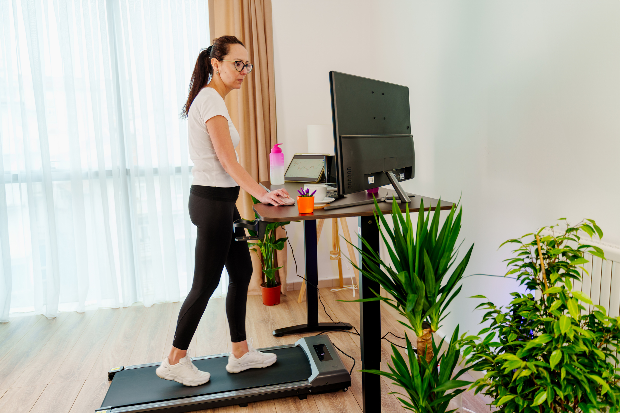 Woman at home office is walking on under desk treadmill