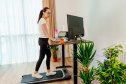 Woman at home office is walking on under desk treadmill