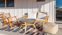 Sunlit patio modern wooden furniture seats, concrete table, colorful rug. Joshua Tree, California.