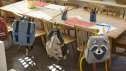 Different types on school backpacks hanging on chair near table in classroom at school