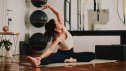 Middle-aged woman practicing pilates stretch on a mat in a bright fitness studio