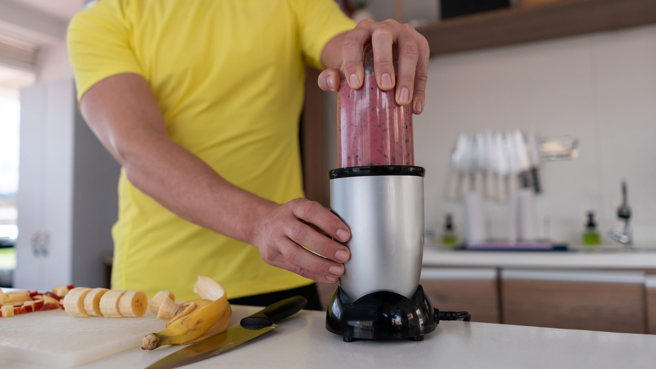 Close-up on a man making a healthy smoothie for breakfast using a blender at home - lifestyle concepts