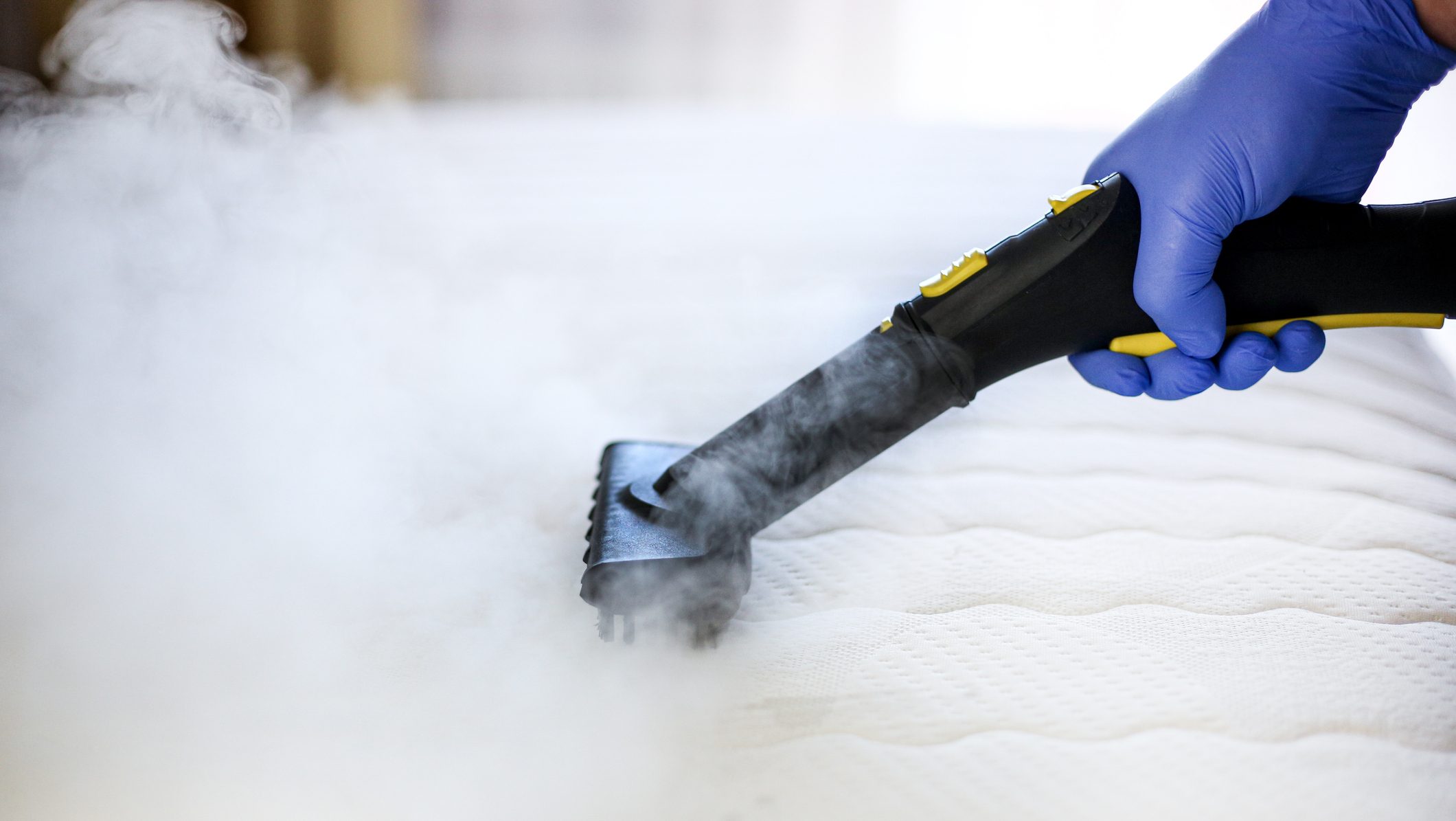 Cleaning and disinfection of the mattress in the bedroom with hot steam. Professional cleaning process