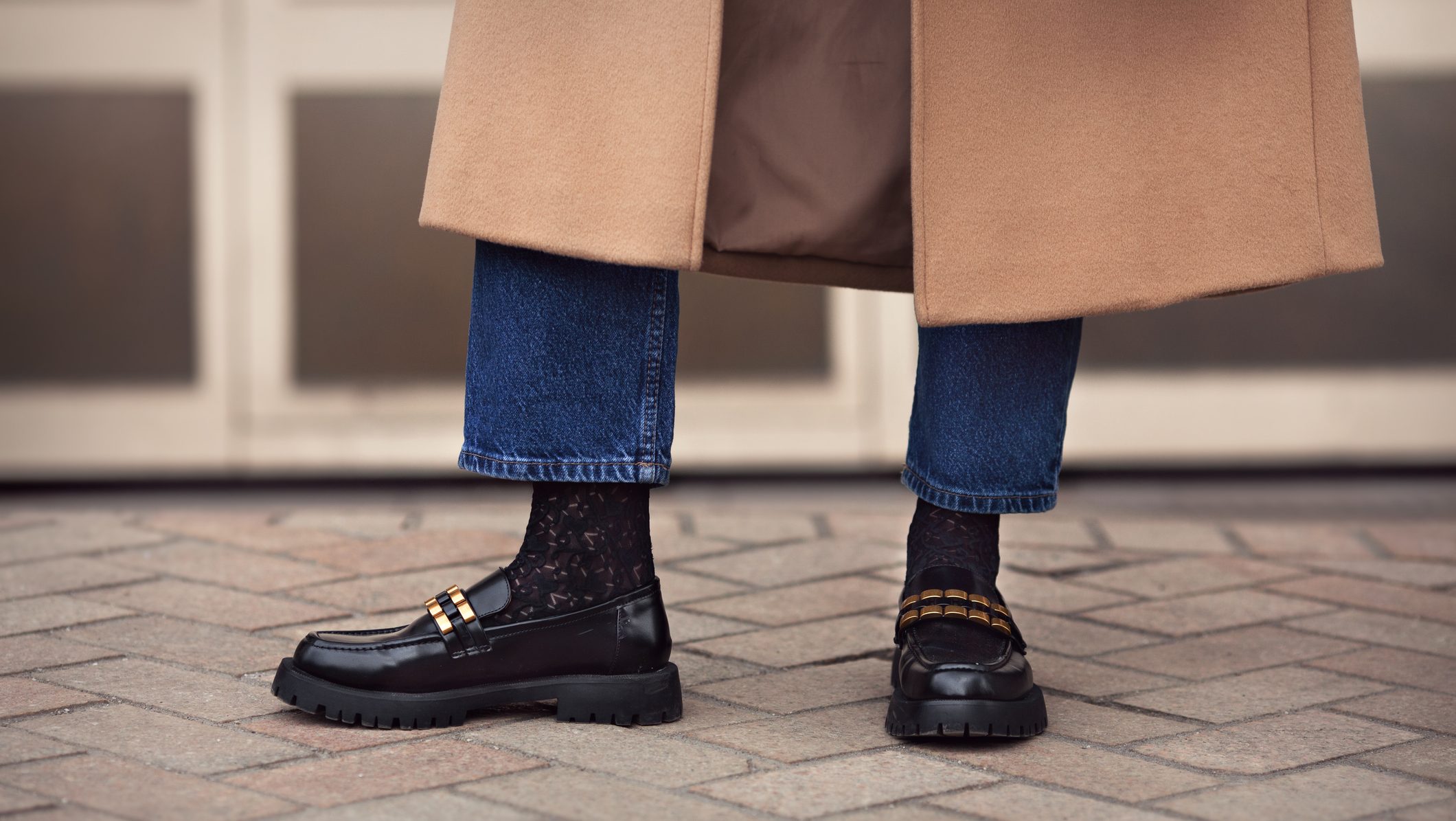 Close up female legs in jeans, stylish black loafers shoes and socks, street style fashion