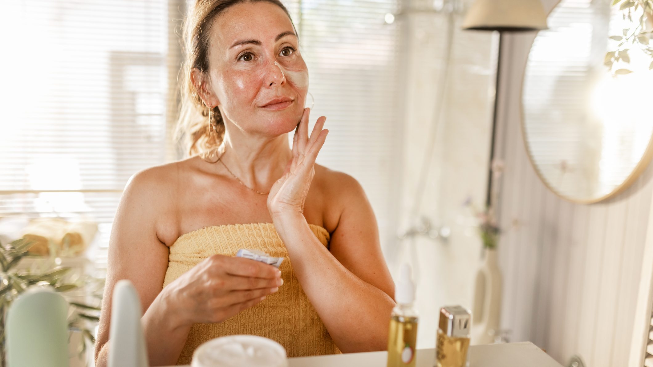 mature woman applying facial mask during her at home skincare and healthy aging routine