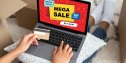 Unrecognizable black lady laying on couch with credit card and laptop with mega sale text on screen, shopping online at home, african american woman having super offer for purchasing on Internet