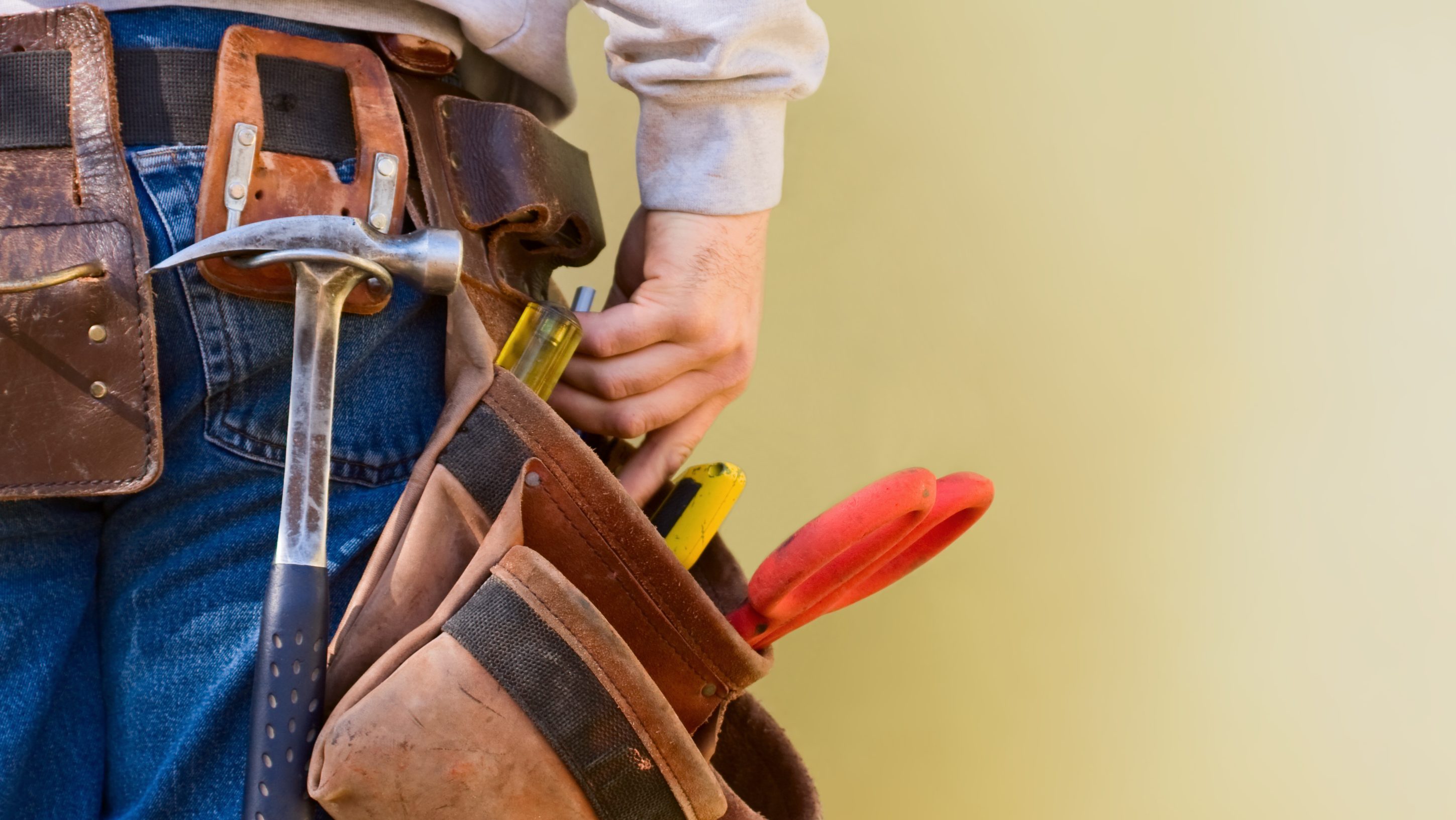 A young construction worker reaches into his tool belt. Copy Space.