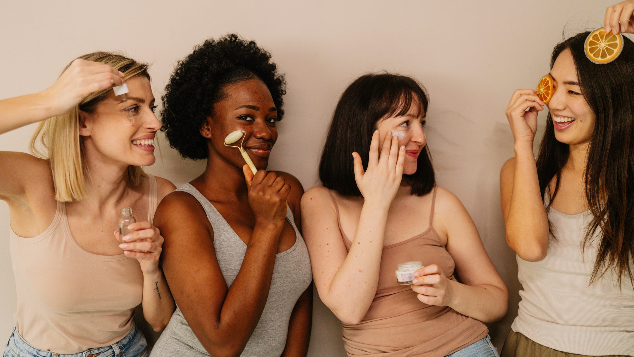 Portrait of a diverse group of an attractive young women, isolated on a white background, taking care of their skin by using different beauty products