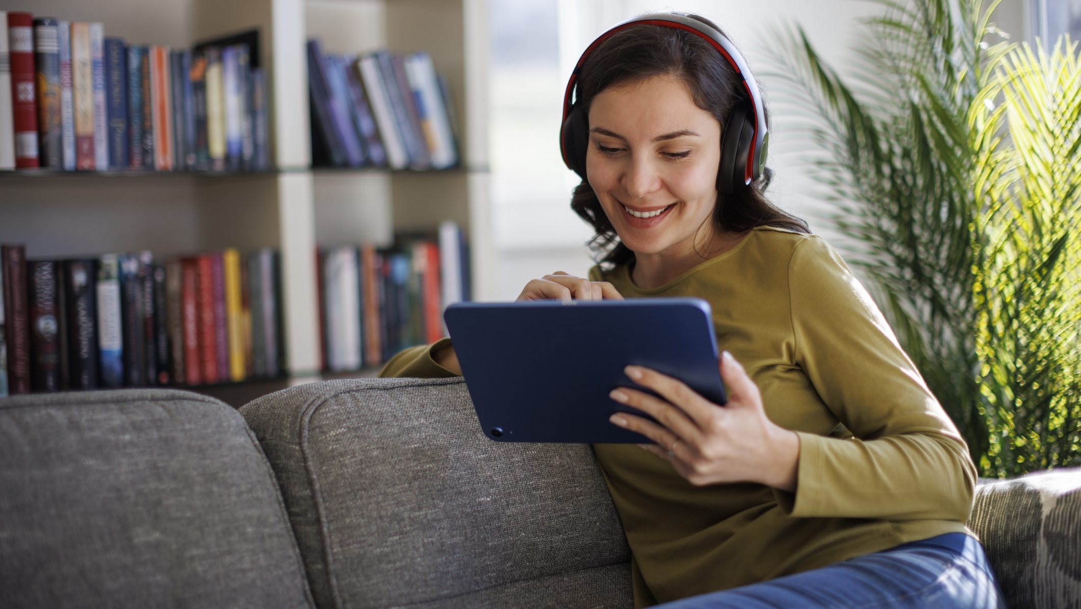 Smiling woman relaxing with digital tablet on couch at home