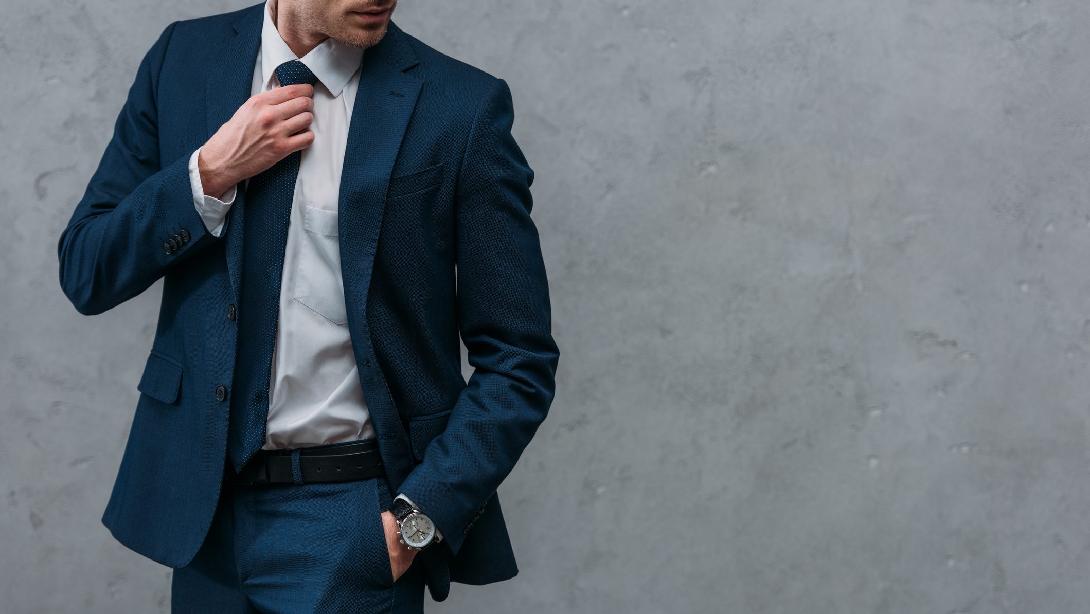 cropped shot of handsome businessman in stylish suit in front of concrete wall