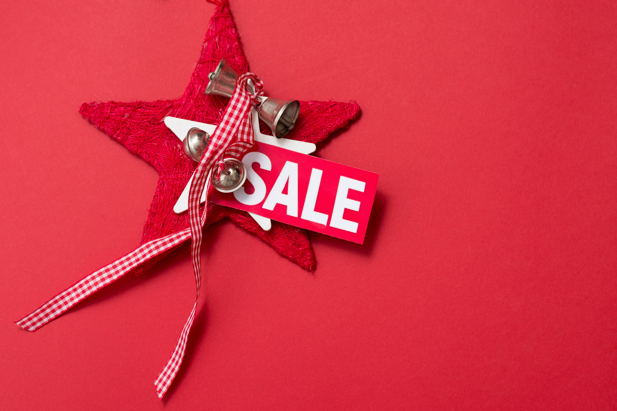 Red background with label sale ans decoration star with bells, copy space