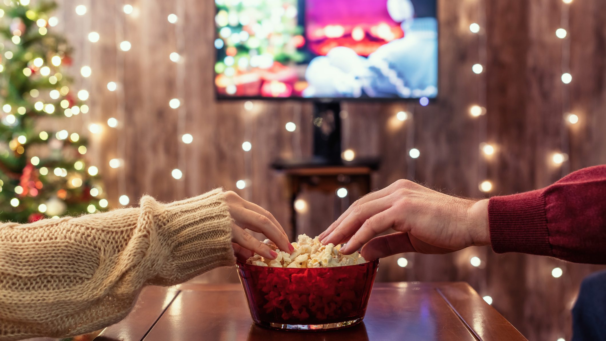Christmas eve. Couple watching tv and eating popcorn. Home cinema. Cropped, close up