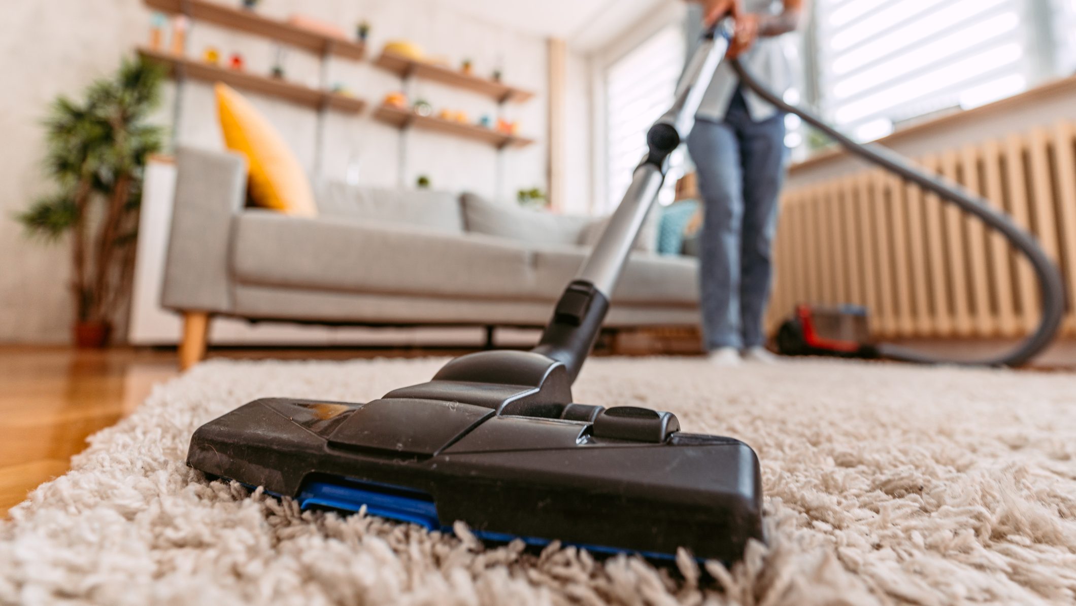 Beautiful senior woman vacuuming the carpet in her apartment. Close-up