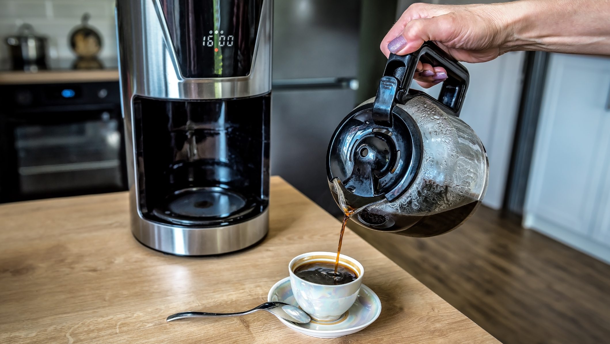 Hand pours ready aromatic coffee into a cup