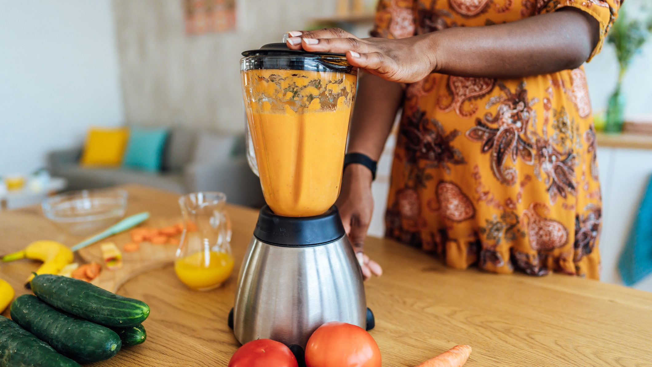 woman making a healthy fruit smoothie in a blender in her home kitchen