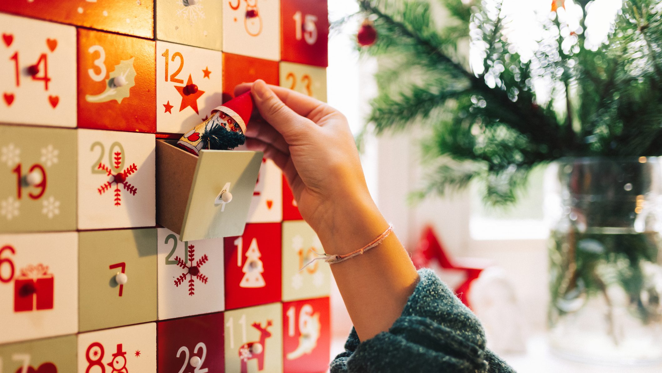 side view on female hand putting chocolate santa claus into old wooden advent calendar
