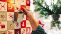 side view on female hand putting chocolate santa claus into old wooden advent calendar